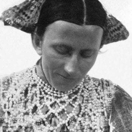 Žena s náhrdelníkom zo sklenených amalgamovaných perál. Lešť okr. Zvolen, prvá polovica 20. storočia.