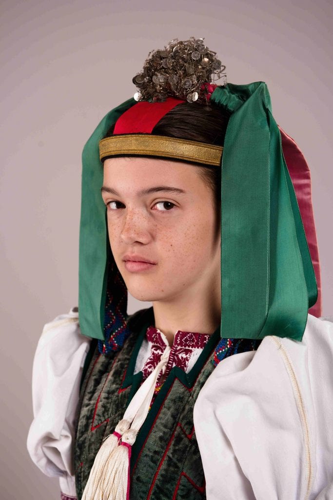 Detail krojovanej ženy so zelenou partou na hlave.