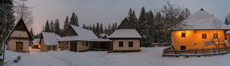 Skupina tradičných obytných domov, zasnežená podvečerná ulica.