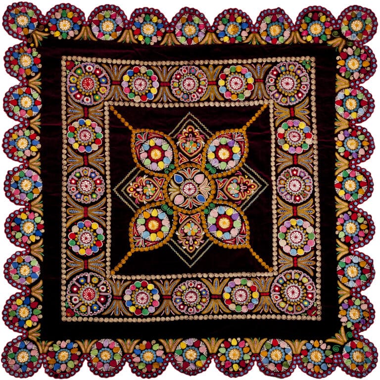 Detail of the embroidery pattern with the dominant colors black and red. The pattern resembles a kaleidoscope.