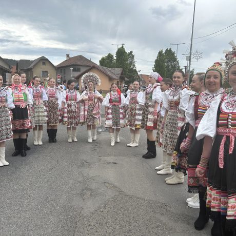 Skupina krojovaných žien na ulici medzi domami.