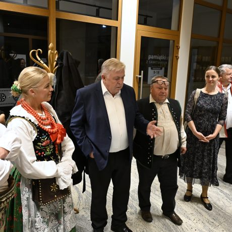 Skupina mužov a žien v tradičnom odeve, ale aj v civilnom spoločenskom odeve stojacich vedľa seba.